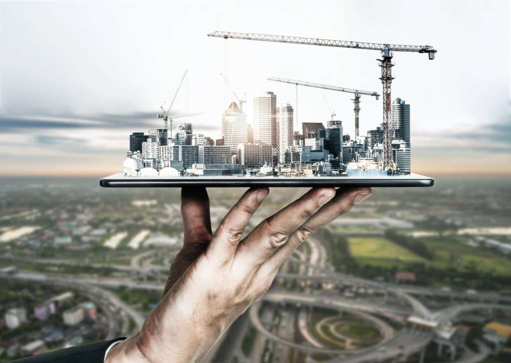 There is a hand holding tablet and showing the projection of Innovative architecture and civil engineering plan